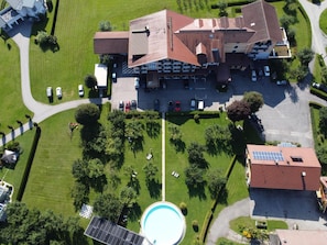 Vista aérea de un hotel con piscina, varios espacios de estacionamiento y zonas verdes circundantes.