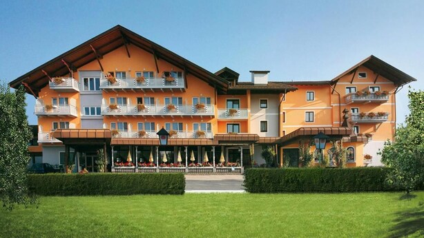Un hotel de varios pisos con techo plano, balcones con jardineras y un área de entrada cubierta.