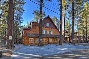 A log cabin with a prominent front porch, multiple windows, and a steeply pitched roof.