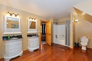 A bathroom with two sinks, a bathtub, and a toilet.