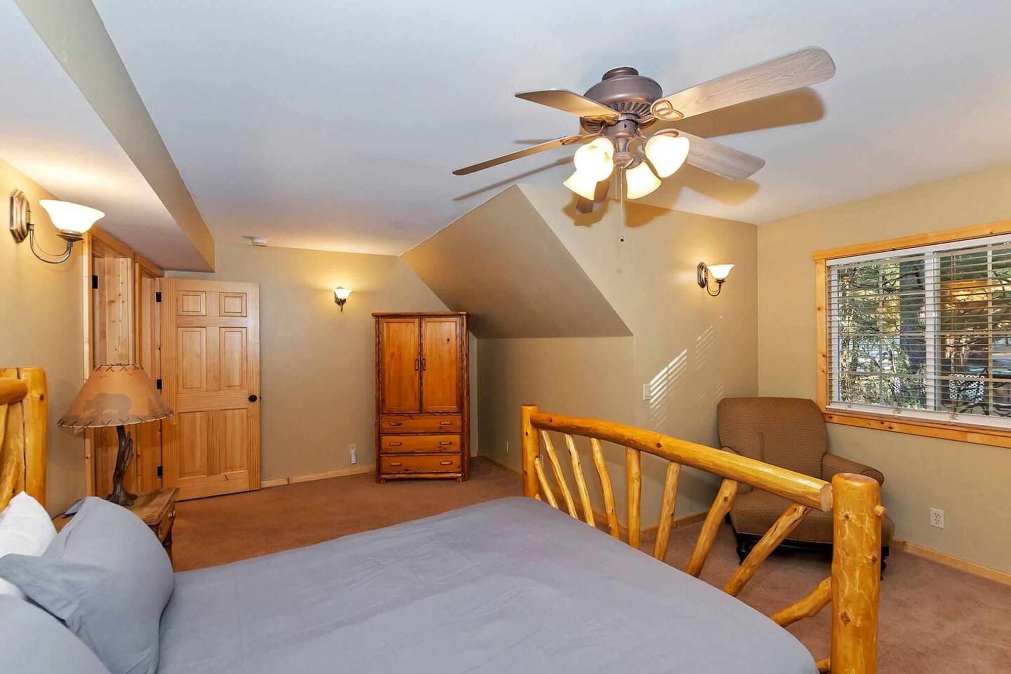 Quarto com cama, ventoinha no teto, guarda-roupa, janela com persianas e luminária.