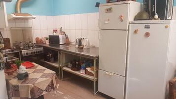 A compact kitchen with white cabinets, a stove, a refrigerator, and a table with a patterned tablecloth.