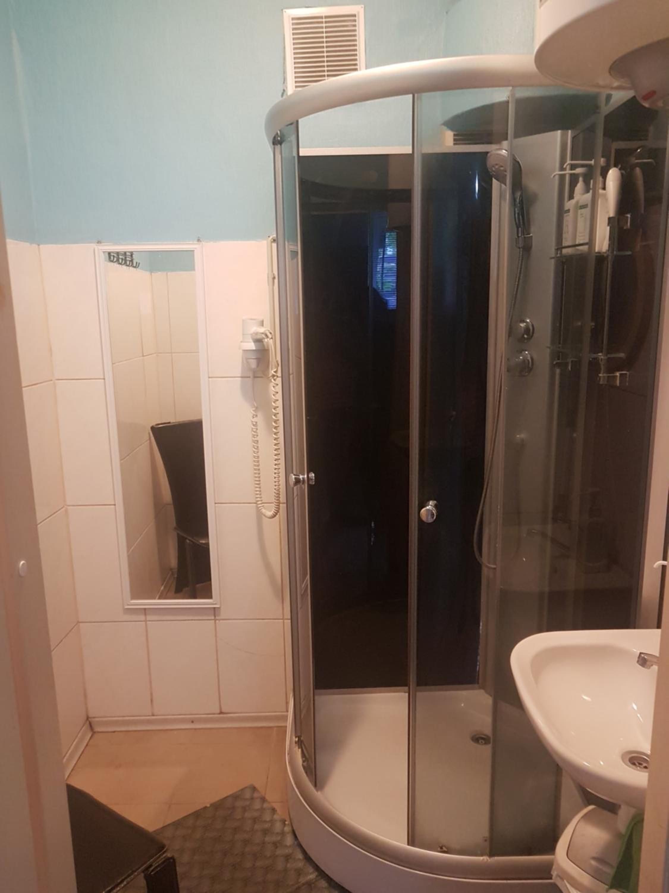 A bathroom with a glass-enclosed shower, a toilet, and a sink.