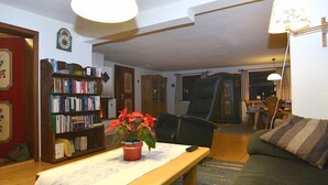 A cozy living room with a wooden bench, a bookshelf, a table with a potted plant, and a green sofa. - Ferienhaus In Bayern Mit Waldblick (Viechtach)