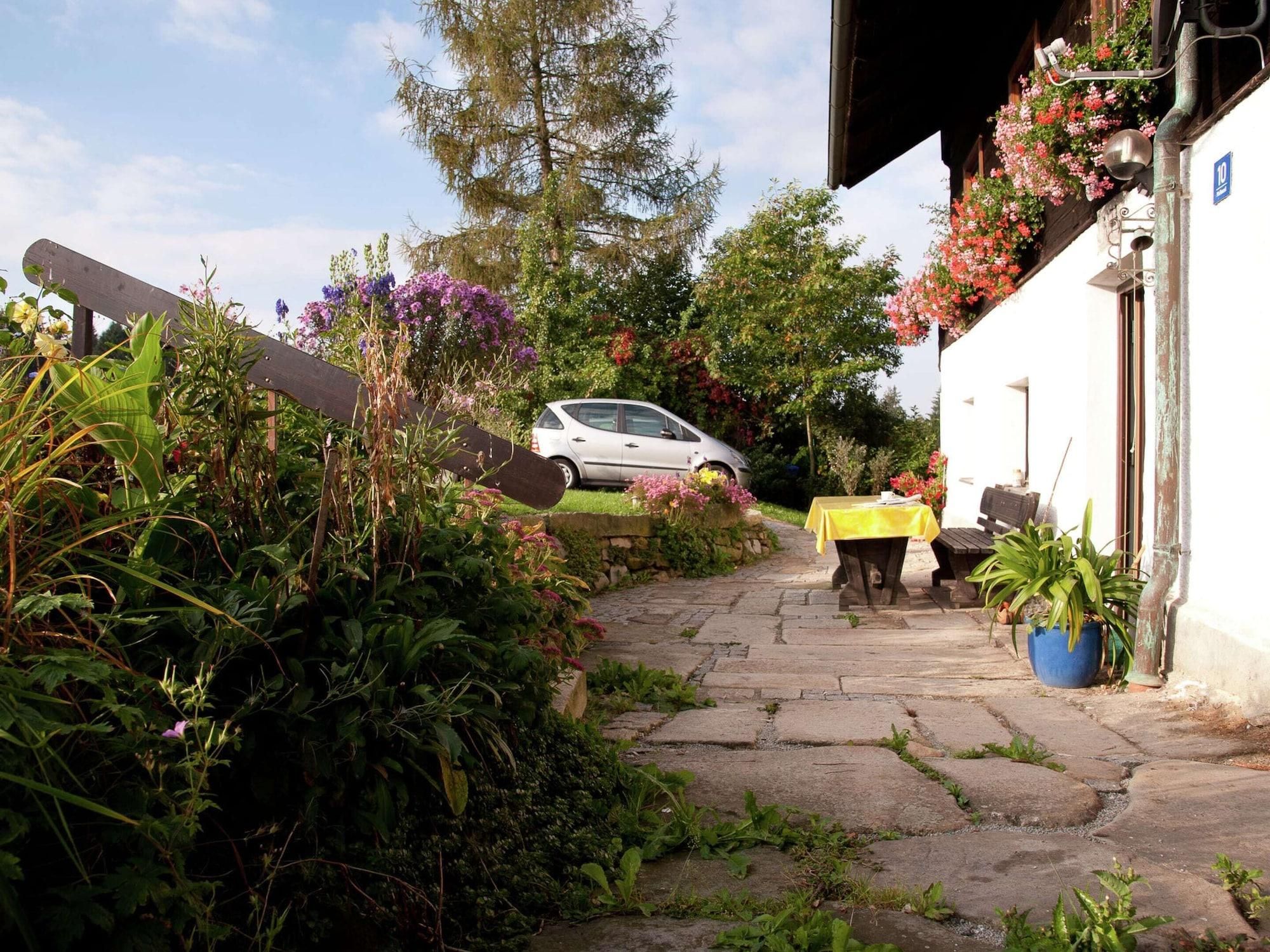 A stone pathway leading to a building with a car parked in the background.