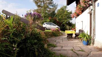 A stone pathway leading to a building with a car parked in the background.