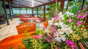 A restaurant with outdoor seating, covered by a transparent roof, and a table center with a floral arrangement. - Hotel Castillo De Gauzón (Castrillon)