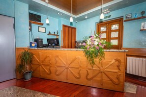 A reception desk with a wooden design, a coffee machine, a television, and a sign indicating the exit. - Hotel Castillo De Gauzón (Castrillon)