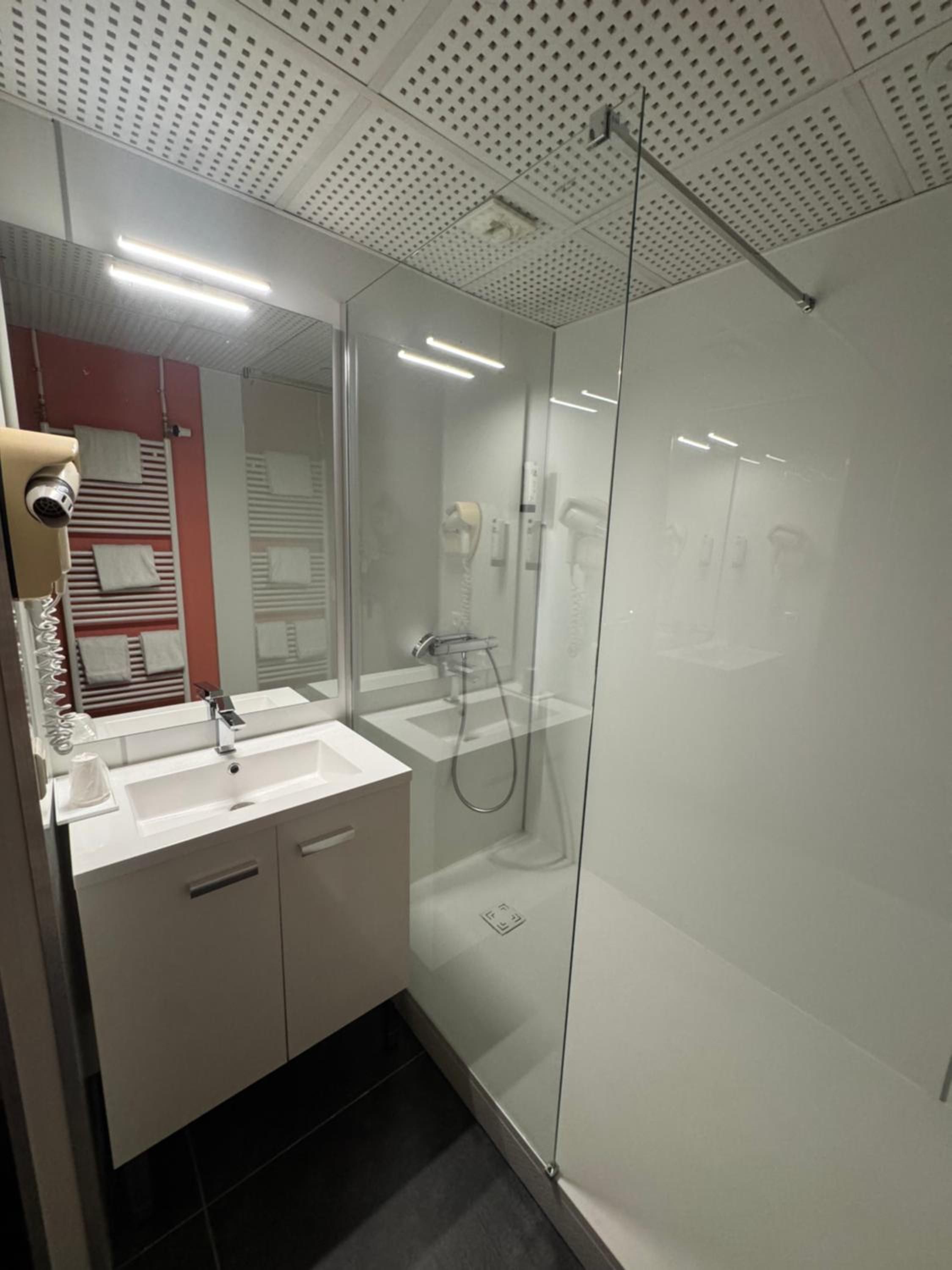 A modern bathroom with a glass-enclosed shower, a double sink vanity, and a visible hairdryer.