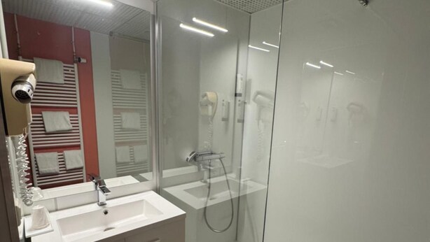 A modern bathroom with a glass-enclosed shower, a double sink vanity, and a visible hairdryer. - Hôtel Restaurant Henry (Puy-l'Eveque)