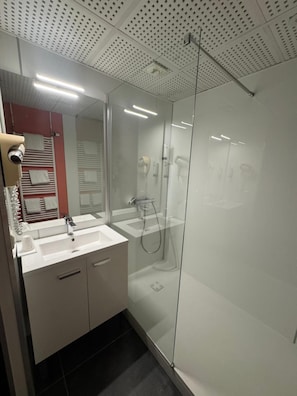 Casa de banho moderna com chuveiro em cabine de vidro, lavatório duplo e secador de cabelo à vista.