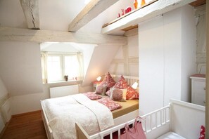 Un dormitorio con techo inclinado, cama con ropa de cama estampada, una ventana y un radiador.