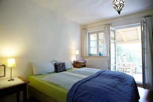 Un dormitorio con cama, lámparas de noche, ventana con cortinas y vistas al exterior.