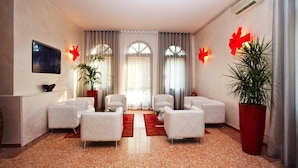 A hotel lobby with a seating area, large windows, and decorative red bows. - Momi's Hotel (Cavarzere)