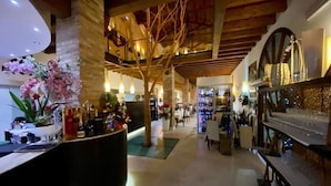A hotel lobby with a curved reception desk, a wooden ceiling, and a staircase in the background. - Momi's Hotel (Cavarzere)