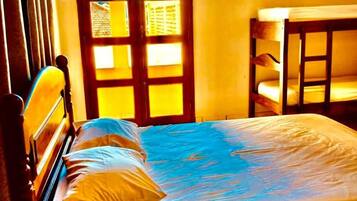 Quarto com cama, cadeira de madeira, mesa pequena e porta com janela.