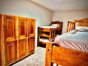 A room with wooden bunk beds and a large wooden wardrobe.
