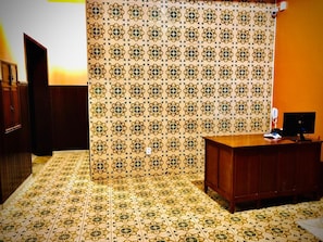 A room with patterned wallpaper, a wooden desk, and a telephone.