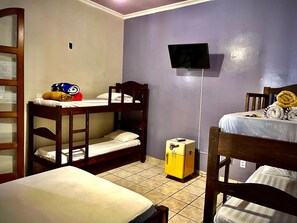 A room with bunk beds, a television mounted on the wall, and a small refrigerator.