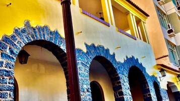 Um edifício com fachada amarela, arcos com padrão azul e um poste de luz.