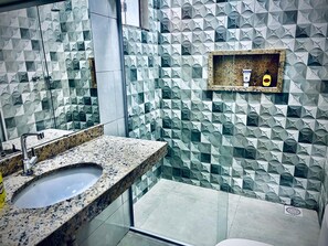 A bathroom with a granite countertop, a sink, and a wall with geometric tile patterns.