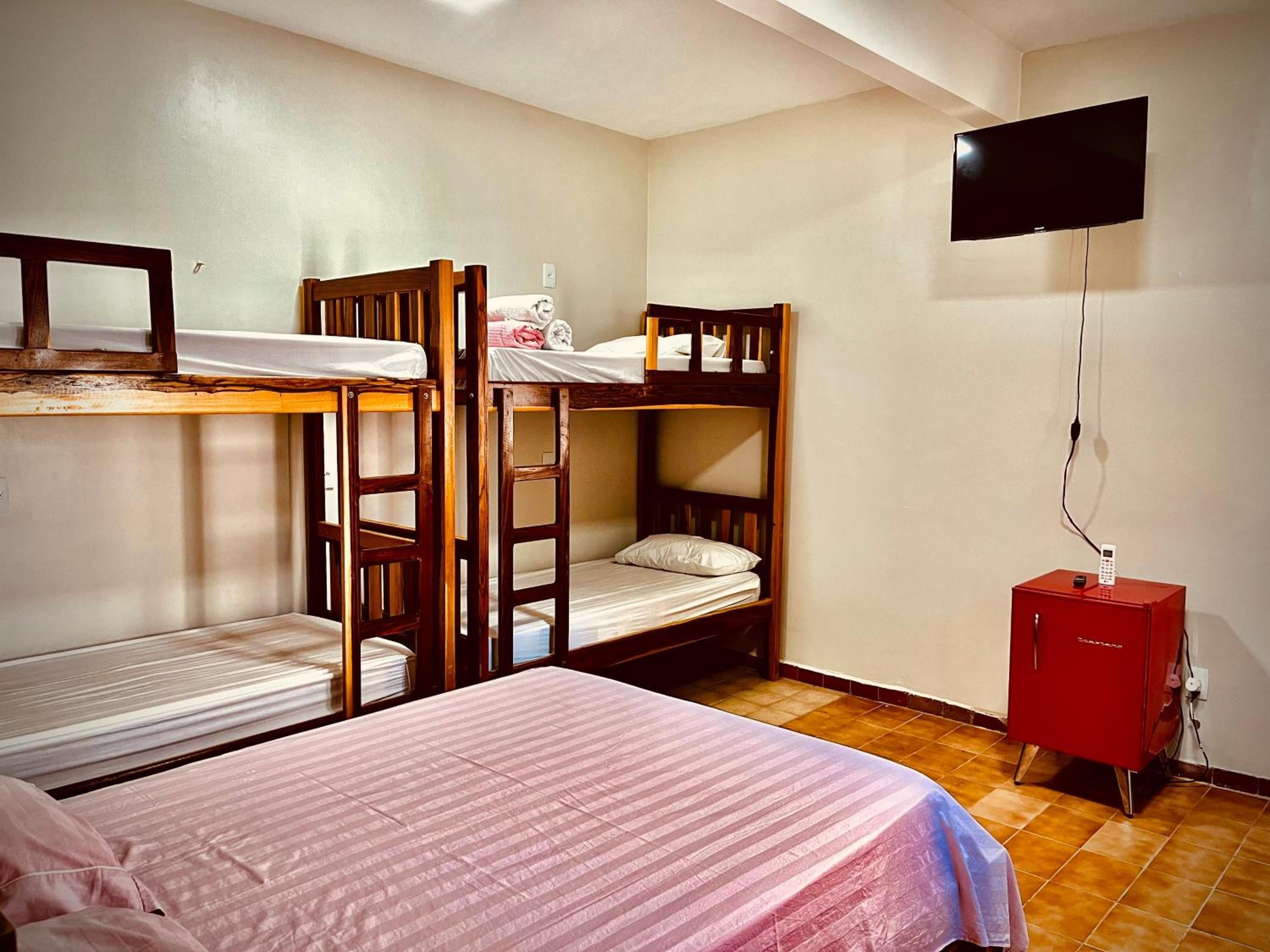 A dormitory room with bunk beds, a television, and a small cabinet.