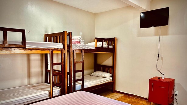 A dormitory room with bunk beds, a television, and a small cabinet.