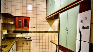 A kitchen with tiled walls, a refrigerator, and wooden cabinets.