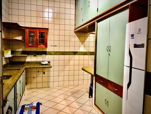 A kitchen with tiled walls, a refrigerator, and wooden cabinets.