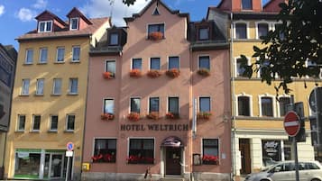 Ein Hotel namens 'HOTEL WELTRICH' mit traditioneller europäischer Architektur, mit zahlreichen Fenstern und Blumenkästen an der Fassade.