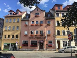 Um hotel chamado 'HOTEL WELTRICH' com estilo arquitetônico europeu tradicional, apresentando várias janelas e caixas de flores na fachada.