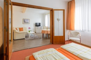 A hotel room with a sofa, a television, a small table, a chair, and a bed.