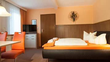 Ein Hotelzimmer mit Bett, Schreibtisch, Stuhl, Fernseher und einer Tür.