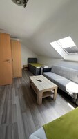 A compact room with a loft bed, a sofa, a small table, and a wardrobe.