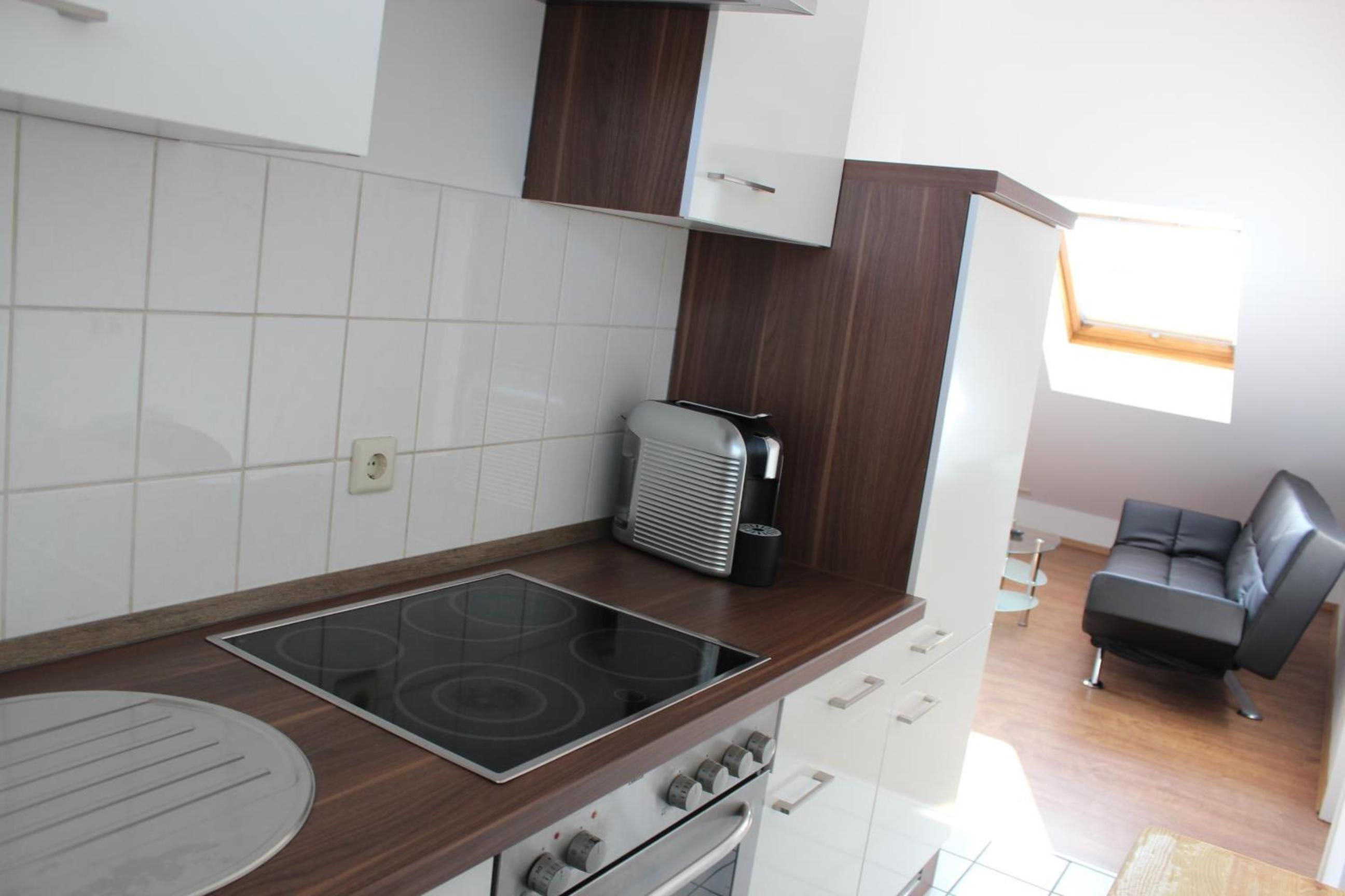 Eine kleine Küche mit eingebautem Herd, Backofen und einem kleinen Fenster.