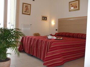 Habitación de hotel con cama doble, una planta en maceta y un radiador.