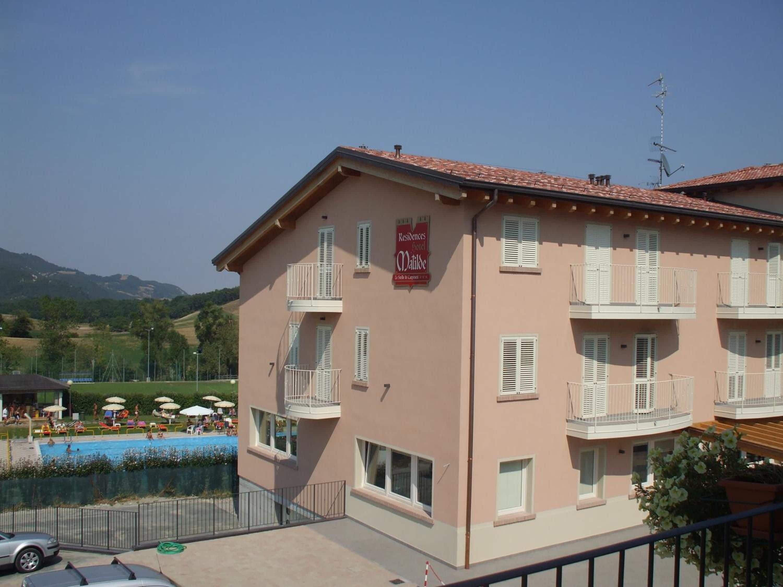 Un hotel de varios pisos con balcones, piscina y un cartel que indica que es un hotel.