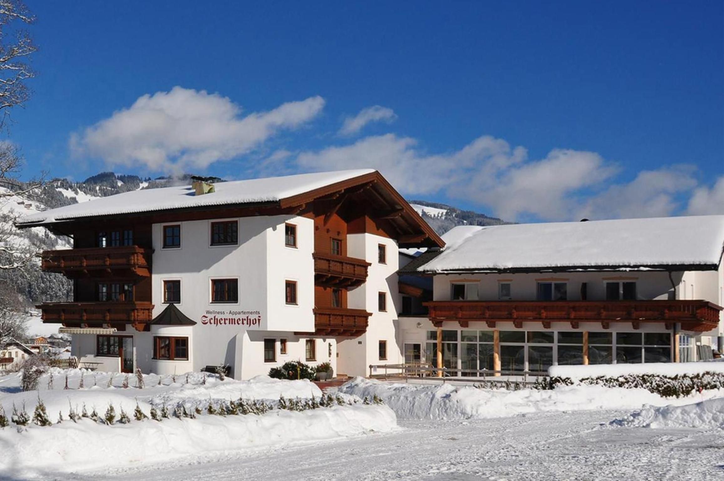 Un hotel de dos pisos con arquitectura alpina tradicional, con balcones de madera y un paisaje cubierto de nieve.