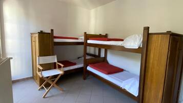 Una camera del dormitorio con letti a castello, una sedia pieghevole e una luce a soffitto.