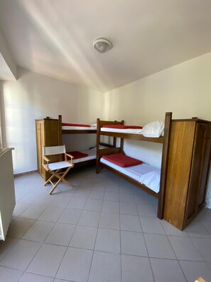 A dormitory room with bunk beds, a foldable chair, and a ceiling light. - Ostello Voltaggio (Voltaggio)