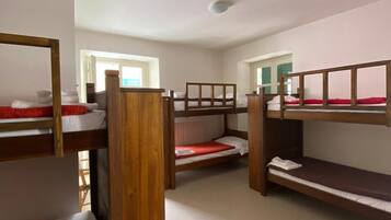 Una camera del dormitorio con letti a castello, una finestra e un termosifone.