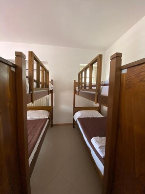 A corridor with bunk beds on either side, leading to a door at the end. - Ostello Voltaggio (Voltaggio)