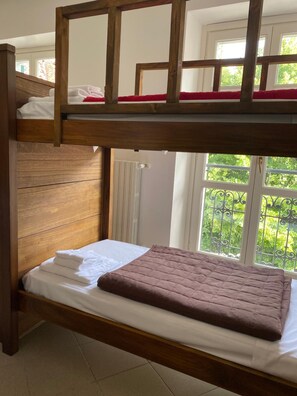 A bunk bed with a wooden frame and a lower bed with a white mattress and a brown blanket. - Ostello Voltaggio (Voltaggio)