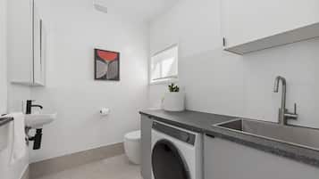 A modern bathroom with a washing machine, sink, and toilet.