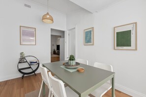 Un comedor con una mesa, sillas y obras de arte en las paredes.