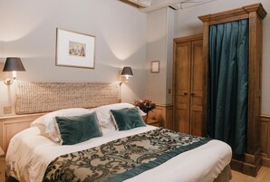 A neatly made bed with a patterned bedspread, two pillows, and two wall-mounted lamps.