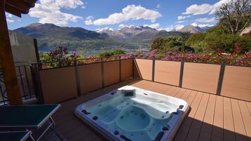Ein Whirlpool auf einer Holzterrasse mit Blick auf die Berge.