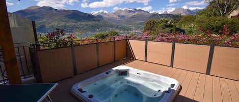 A hot tub on a wooden deck with a mountain view.