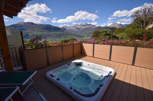 Una vasca idromassaggio su un pontile in legno con vista sulle montagne.
