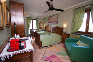 Un dormitorio con dos camas, un escritorio con un electrodoméstico rojo, un sofá verde y un ventilador de techo.